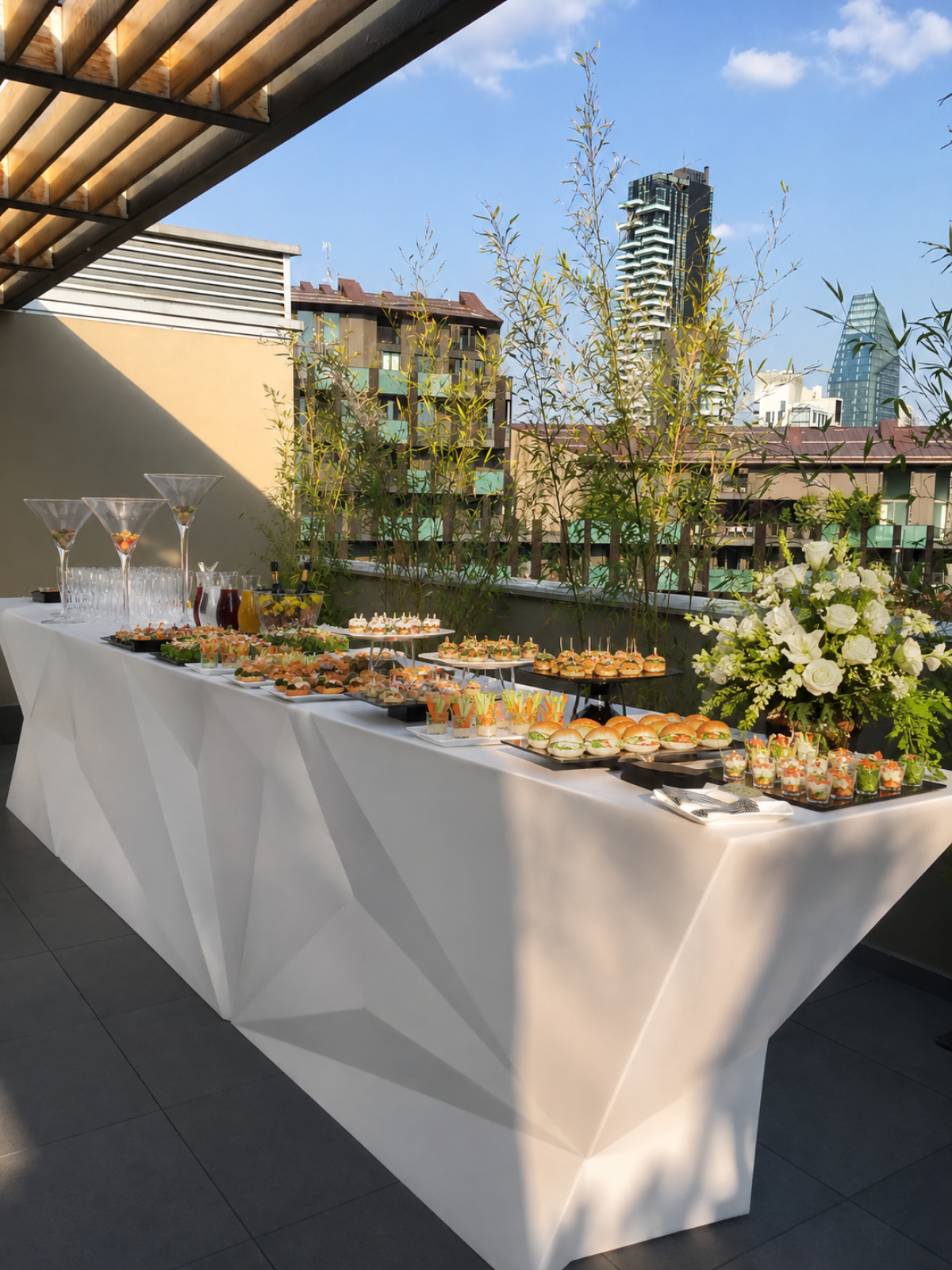 Buffet per cocktail party in terrazza a Milano allestito da Food Mood Banqueting con finger food, mini burger e open bar.