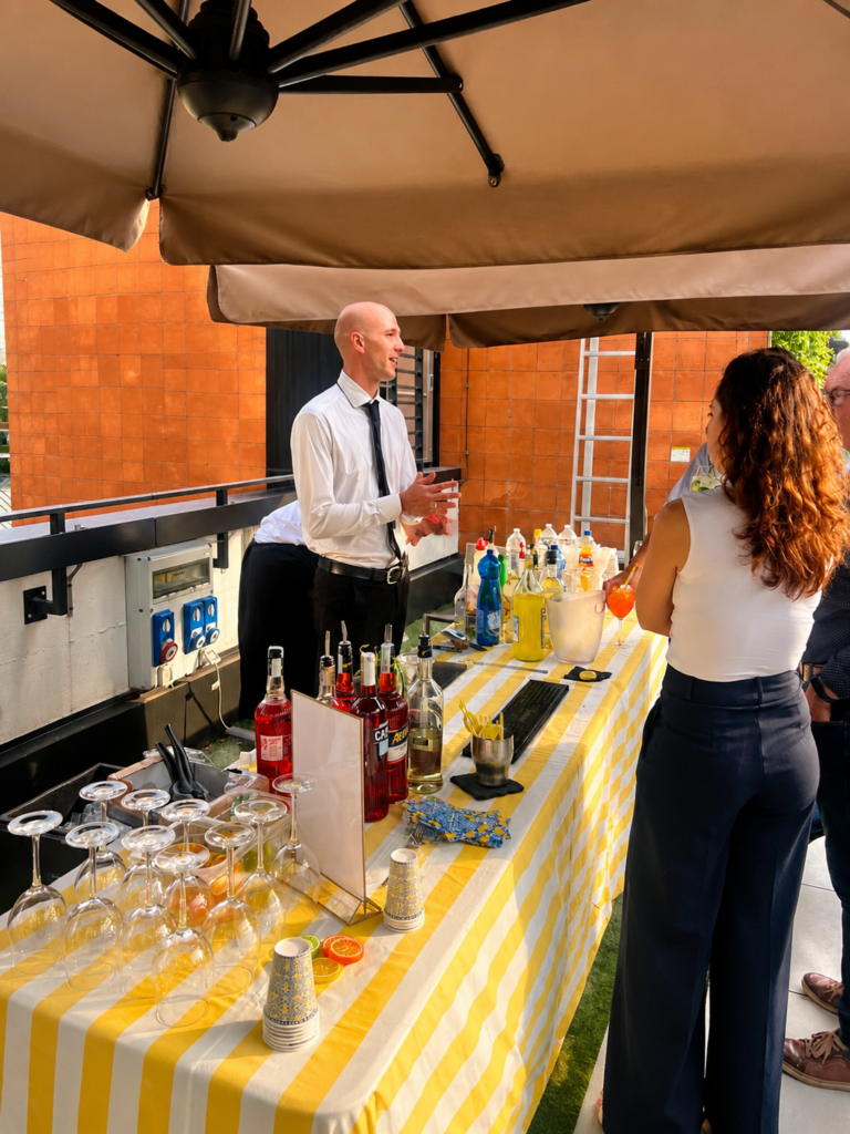 Bartender professionista di Food Mood prepara cocktail durante un servizio open bar per evento aziendale a Milano con allestimento elegante e drink preparati al momento.